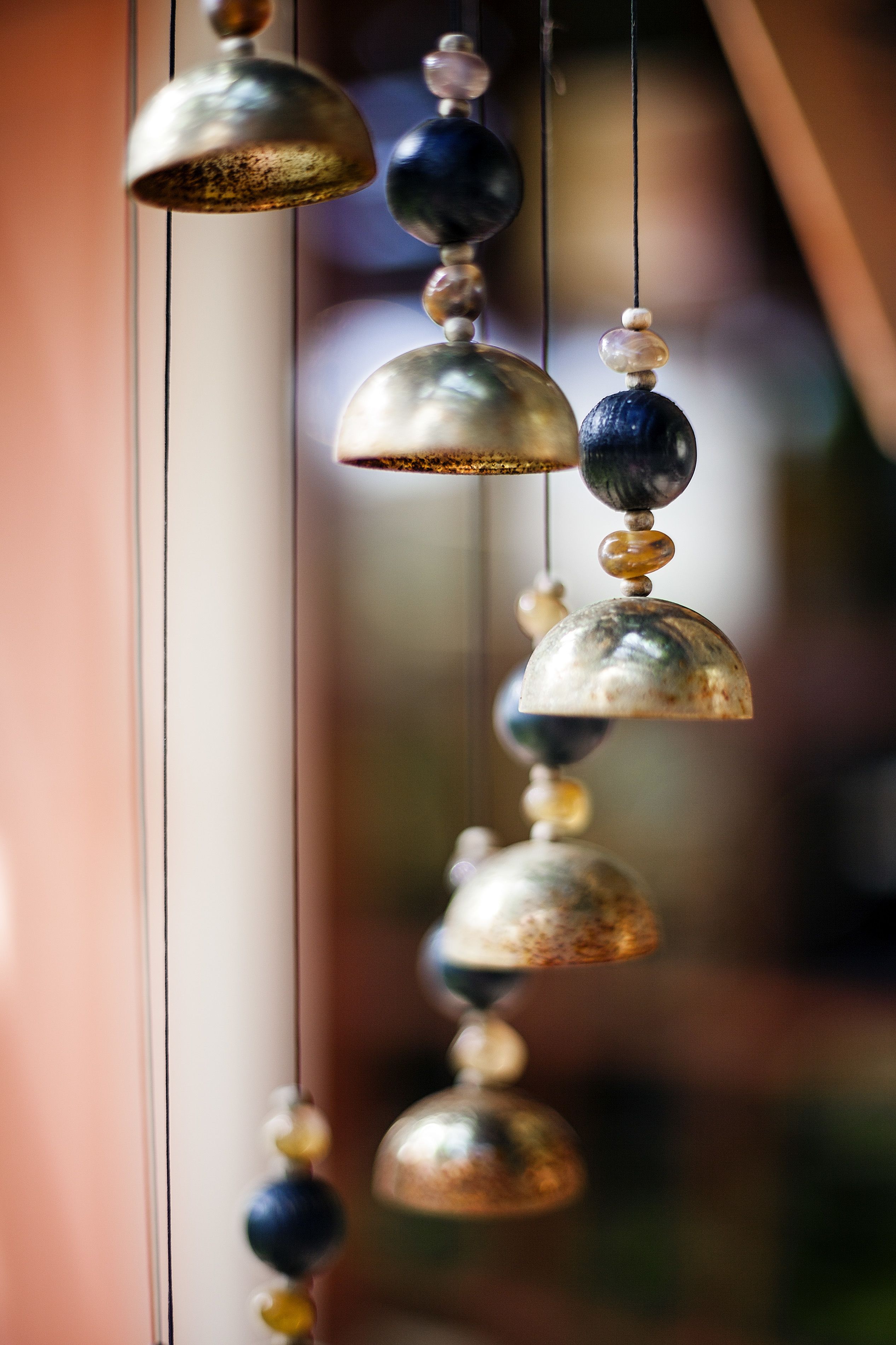 A decorative wind chime with variously sized and colored beads and metal bells.