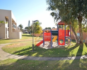 Children can play on the slide and climbing structure in this well-maintained playground area.