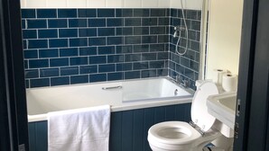 A bathroom with a white toilet, a bathtub, and a shower. - The Wilcove Inn (Torpoint)