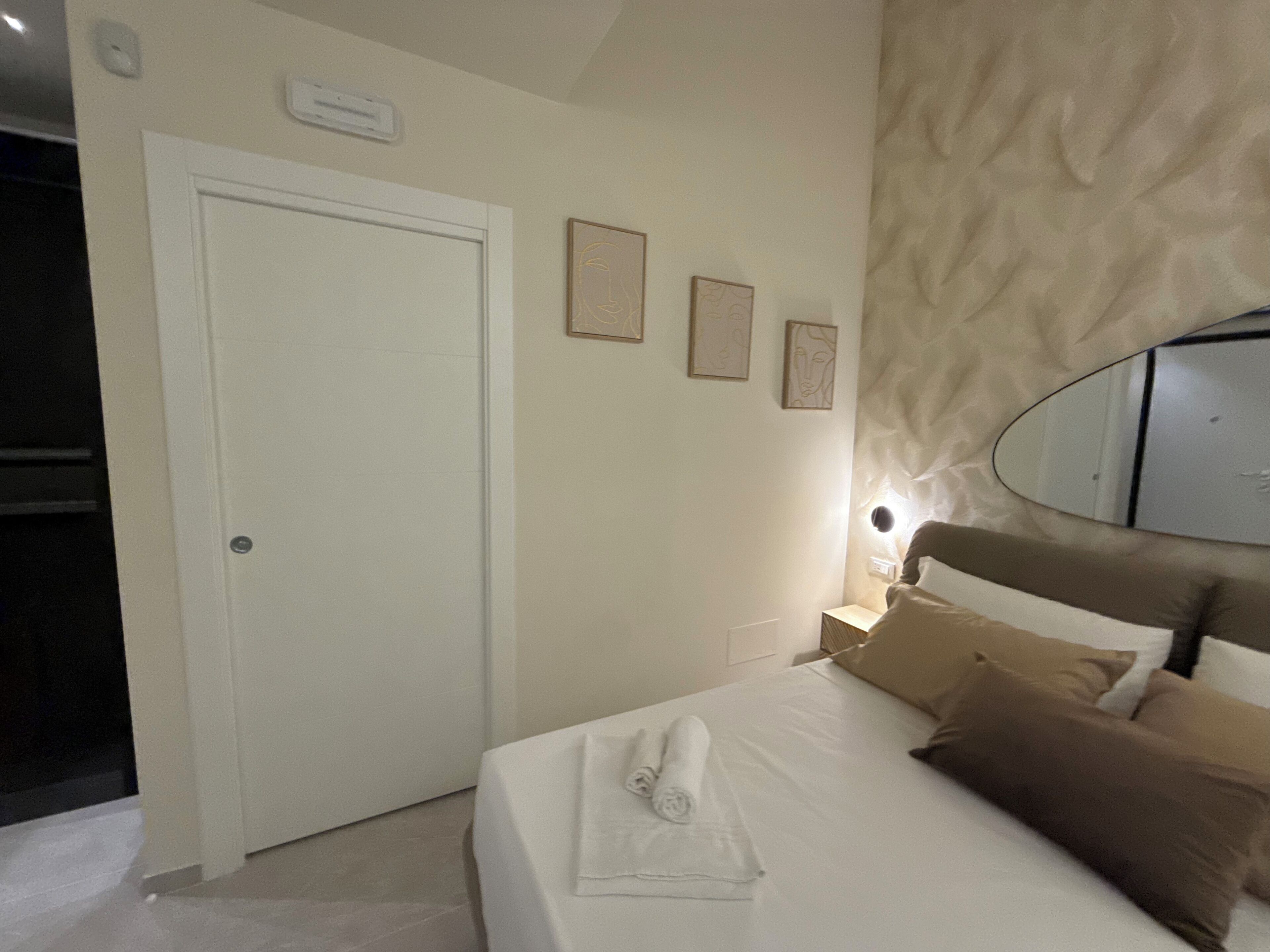 Una habitación de hotel con cama, puerta y espejo fijado a la pared.
