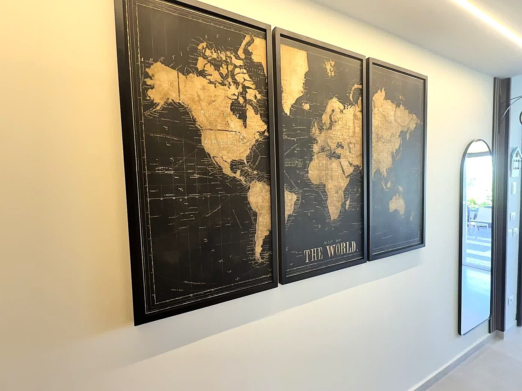 Tre mappe del mondo incorniciate appese al muro.