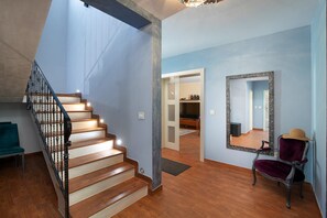 Eine Treppe mit Holzsitzen und schwarzen Geländern, ein Spiegel an der Wand und ein Stuhl mit Hut.