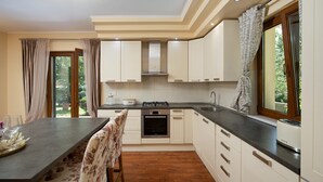 Une cuisine moderne avec des meubles blancs, un îlot central et une fenêtre agrémentée de rideaux.