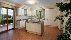 Une cuisine moderne dotée d’un îlot central, de meubles blancs et d’une grande fenêtre.