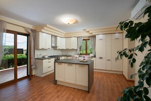 Eine moderne Küche mit einer zentralen Kochinsel, weißen Schränken und einem großen Fenster.
