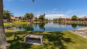 A residential area with a large, calm water body, likely a pond or lake, surrounded by well-maintained lawns and trees. - Modern Chandler Home - Heated Pool, Golf, Fire Pit (Chandler)
