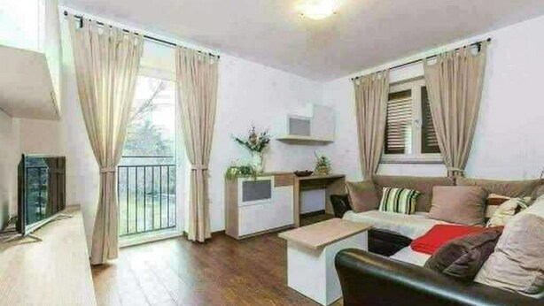 A modern living room with a sofa, coffee table, and a small kitchen area. - Apartments Nika (Vinodol)