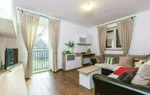 Ein modernes Wohnzimmer mit Sofa, Couchtisch und einer kleinen Küchenzeile.