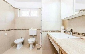 A bathroom with a toilet, bidet, and sink.