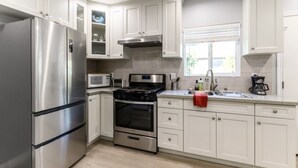 Una cocina moderna con electrodomésticos de acero inoxidable, armarios blancos y un ventanal que proporciona luz natural.