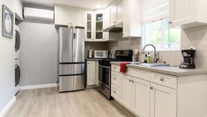 Una cocina moderna con electrodomésticos de acero inoxidable, armarios blancos y un ventanal que proporciona luz natural.
