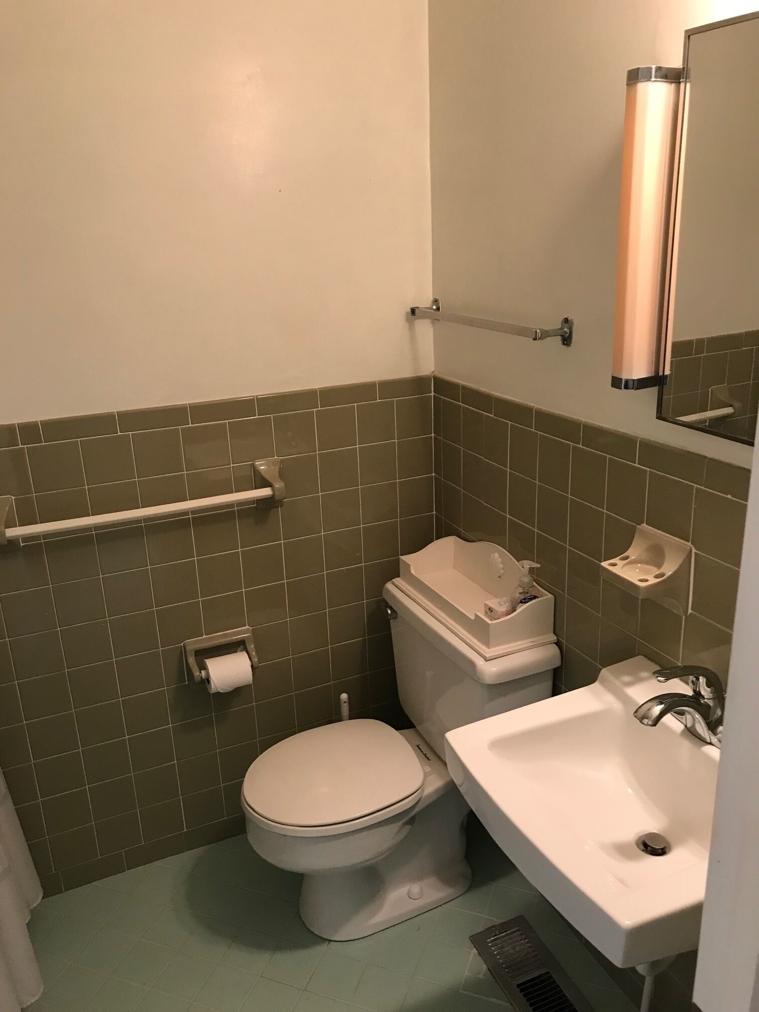 A small bathroom with a toilet, sink, and a mirror.