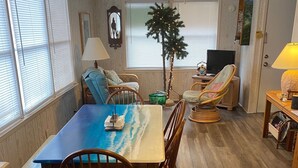 A dining area with a table and chairs, a ceiling fan, a Christmas tree, and a television.