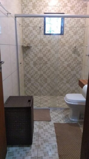 Une salle de bain avec une douche, des toilettes et une petite fenêtre.