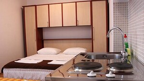 A compact hotel room with a bed, a small kitchenette with a stove, and a sink. - Apartmani Krka Rooms (Sibenik)