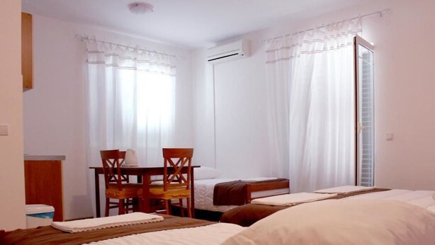 A hotel room with two beds, a dining table, and chairs. - Apartmani Krka Rooms (Sibenik)
