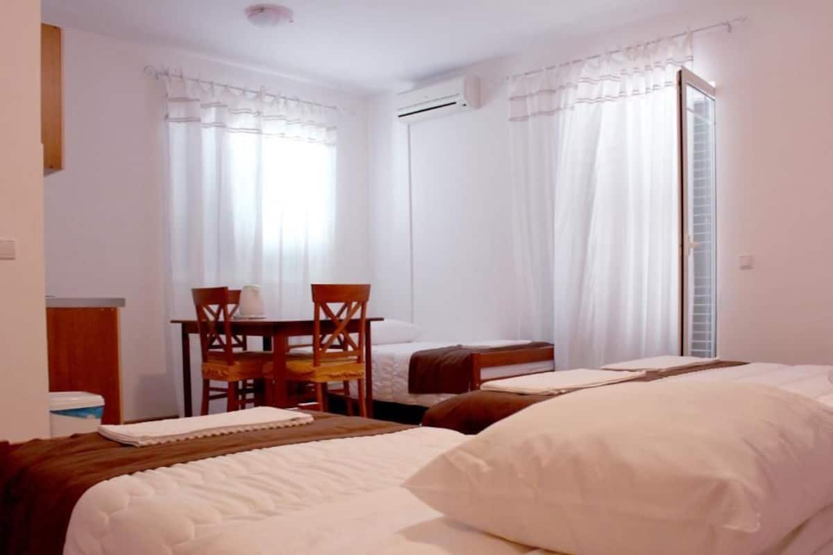 Ein Hotelzimmer mit zwei Betten, einem Esstisch und Stühlen.