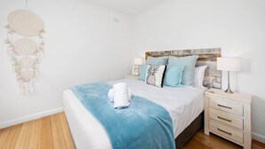 A bedroom with a bed, bedside tables, a dreamcatcher, and a wall-mounted headboard.