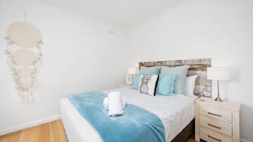 Ein Schlafzimmer mit einem Bett, Nachttischen, einem Traumfänger und einem an der Wand befestigten Kopfteil.