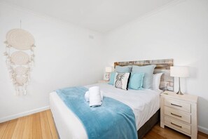 A bedroom with a bed, bedside tables, a dreamcatcher, and a wall-mounted headboard.