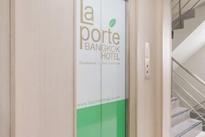 L'entrée d'un hôtel, avec une enseigne indiquant « La Porte Bangkok Hotel ».