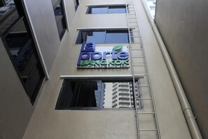 Een gebouw met een bord waarop 'le porte BANGKOK' staat, en een zichtbaar raam.