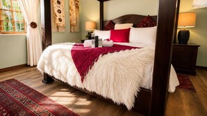 A four-poster bed with a white and red blanket, a nightstand with a lamp, and a window with curtains. - Moonriver Guesthouse (Upington)