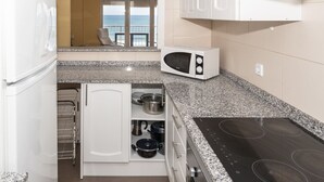 A compact kitchen with a microwave, stove, and small refrigerator. - FRONTALMAR, ESC-B, 8º-32 (Cullera)