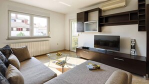 A modern living room with a sofa, TV, and built-in shelving. - Apartment Marko (Pula)