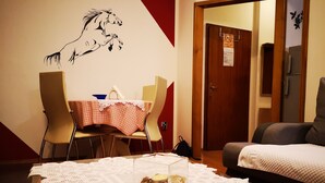 Una habitación con una mesa de comedor cubierta por un mantel a cuadros, un mural de un caballo en la pared, una puerta con un letrero y un sofá.
