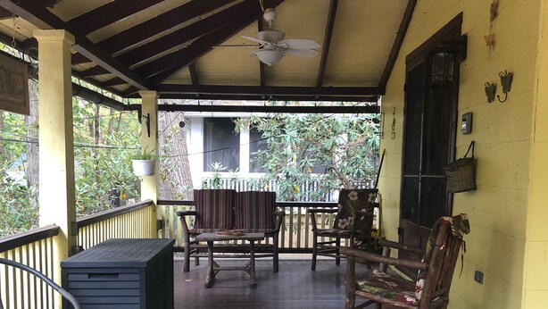 A covered porch with wooden flooring, a ceiling fan, and a seating area with chairs and a table. - Butterfly Cottage Close to Everything (Mt Gretna)