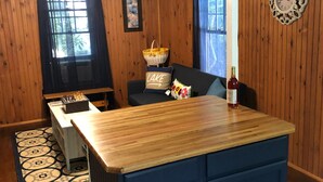 A kitchen with wooden walls, a central island, a dining table, and a chandelier. - Butterfly Cottage Close to Everything (Mt Gretna)