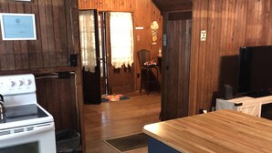 A kitchen with wooden walls, a stove, a sink, and a wooden countertop. - Butterfly Cottage Close to Everything (Mt Gretna)