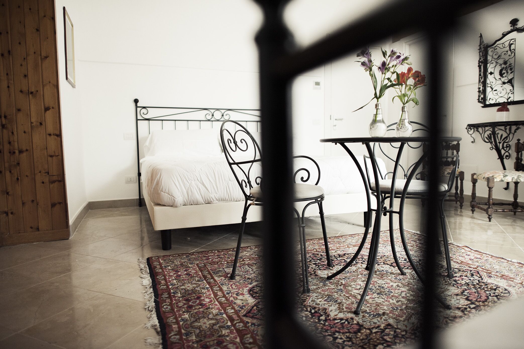 A bedroom with a bed, a chair, a table, and a rug.