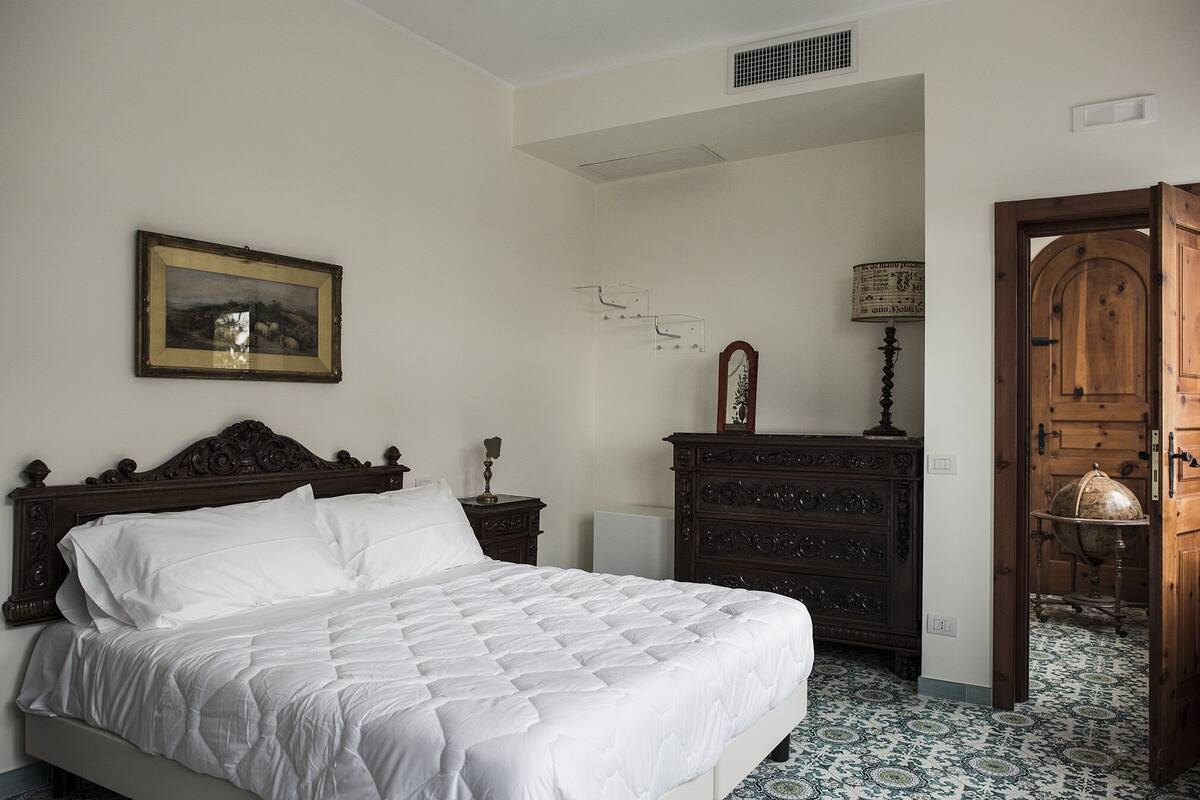 A bedroom with a large bed, a dresser, a mirror, and a globe.