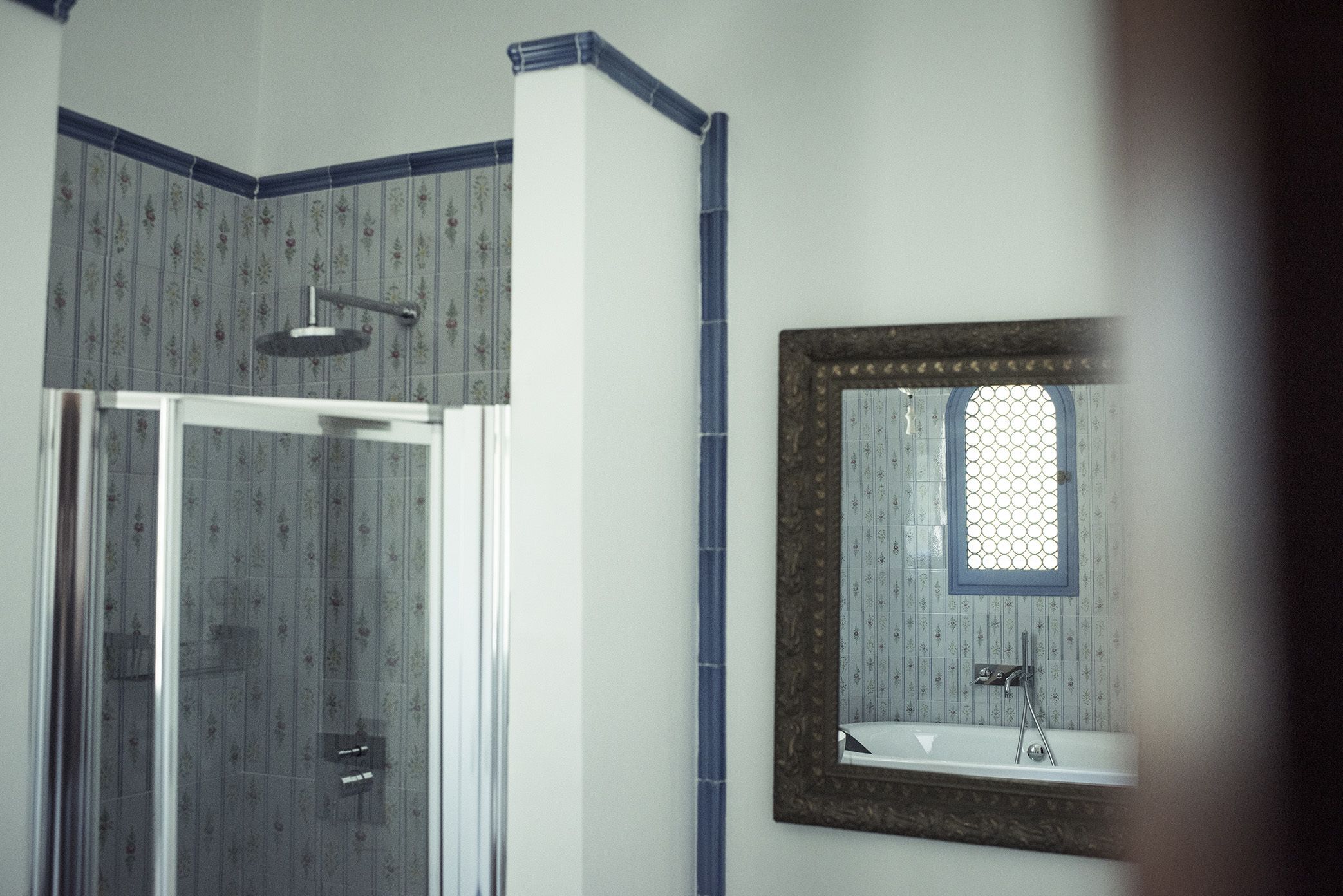 Ein Badezimmer mit Dusche, Waschbecken und einem Spiegel mit dekorativem Rahmen.
