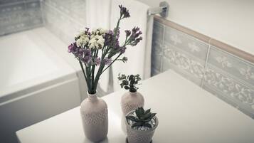 Two vases with flowers and a succulent on a bathroom counter.