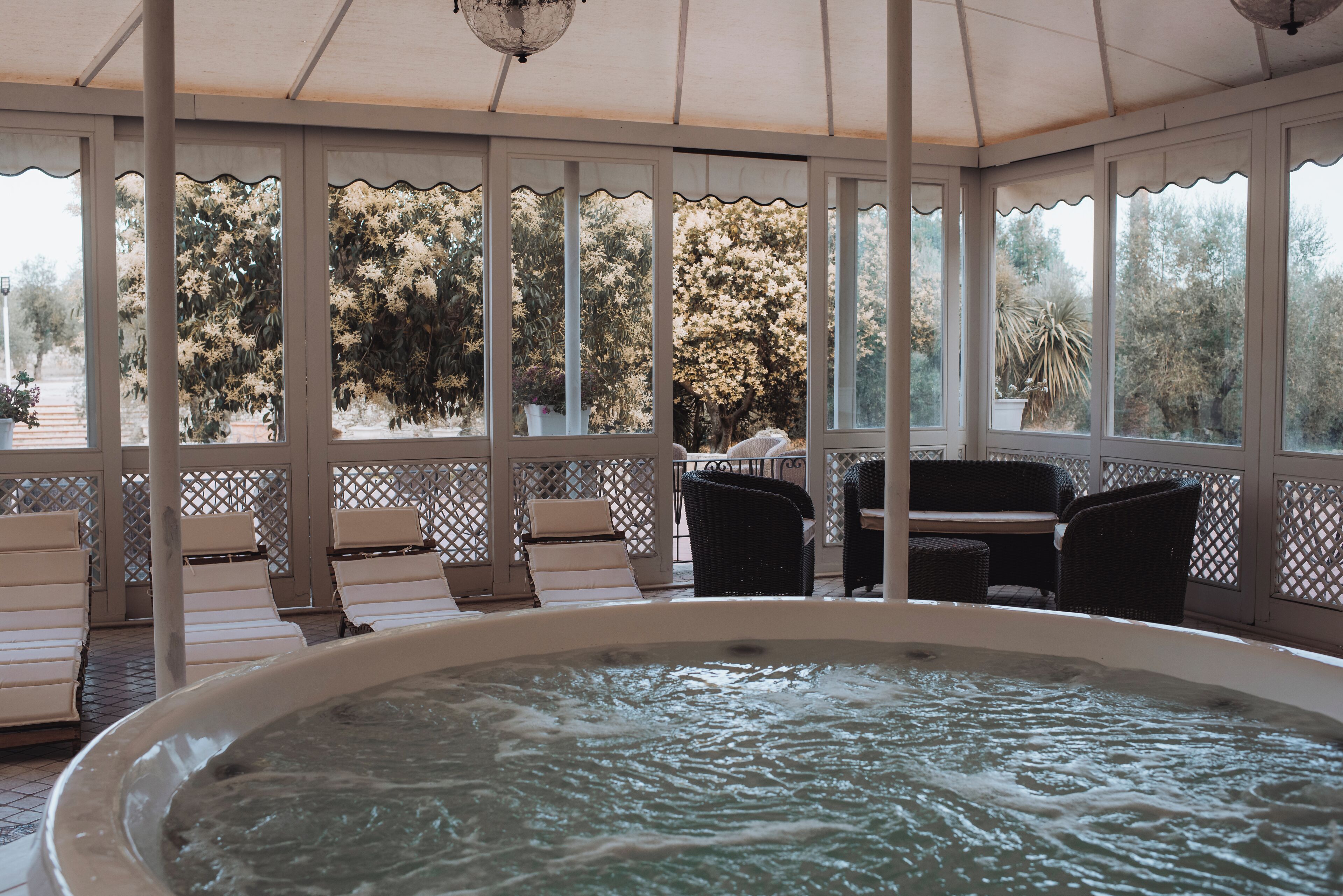 A hot tub area with lounge chairs and a view of trees.