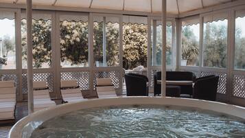 A hot tub area with lounge chairs and a view of trees.