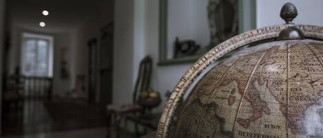 En globus med detaljeret kort, et spejl og en lysekrone i et svagt oplyst rum.