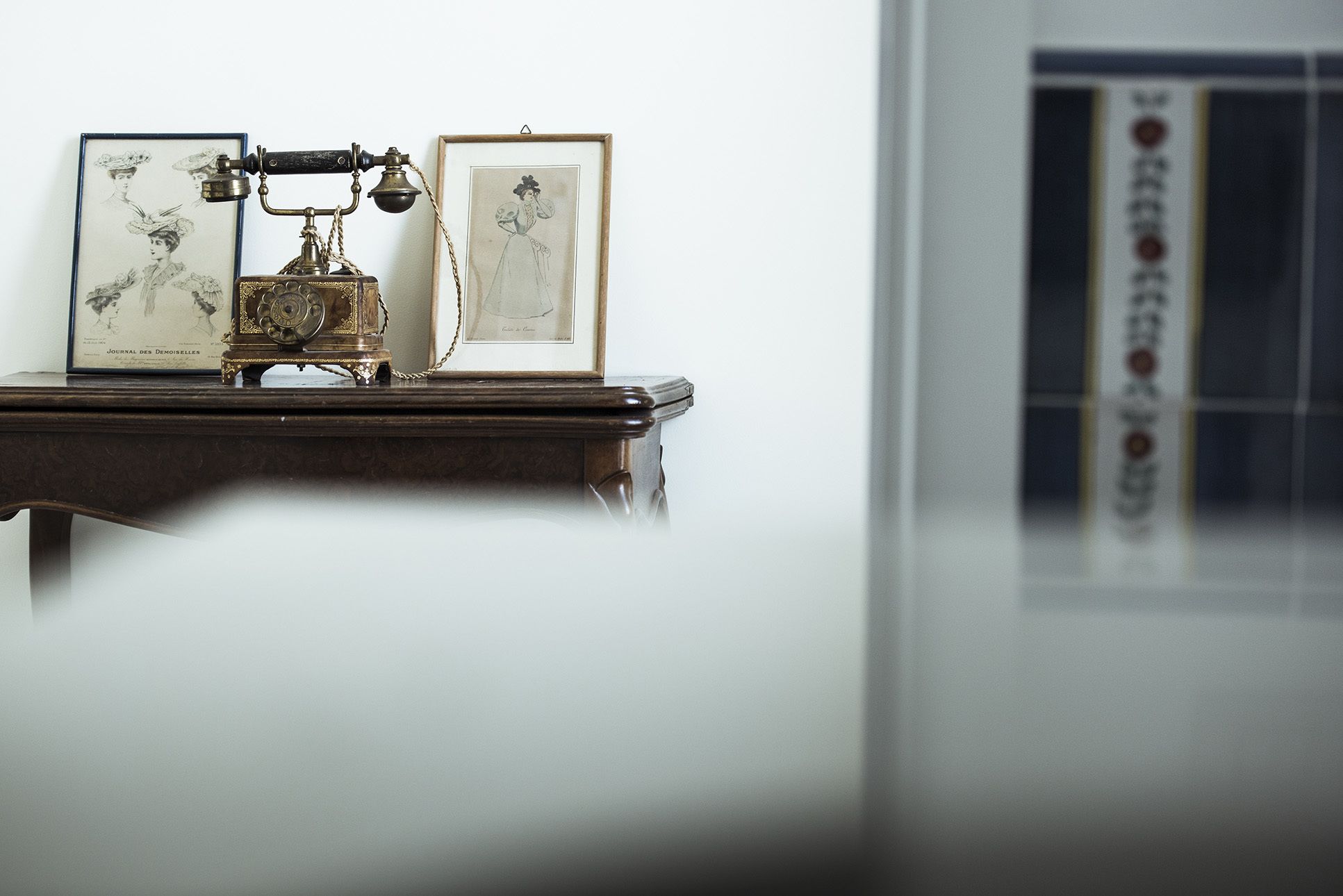 A vintage typewriter on a wooden table with two framed pictures beside it.