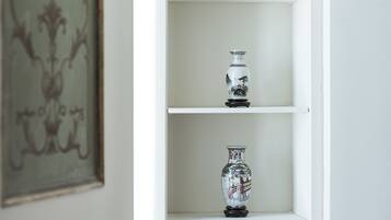 Una estantería blanca abierta con jarrones decorativos y una cesta tejida.