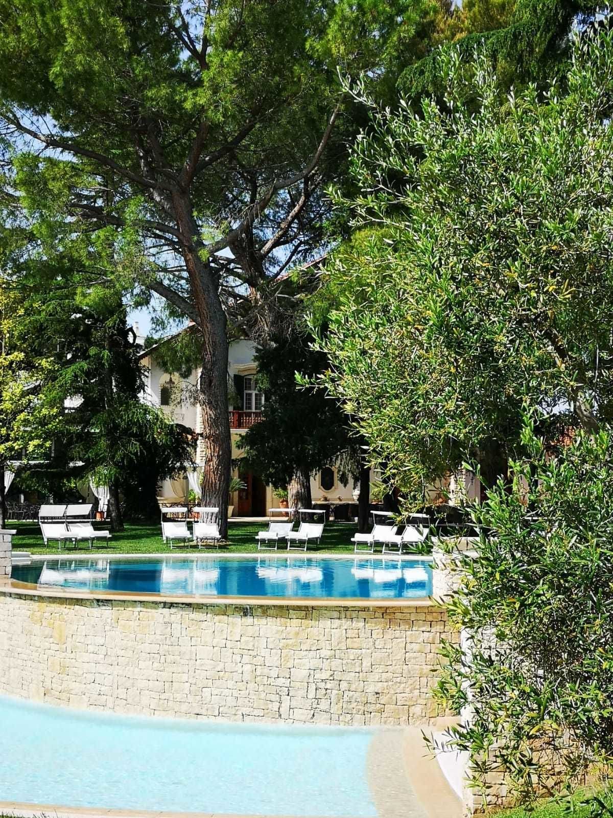 Un área de piscina con sillas de descanso y una pared de piedra.