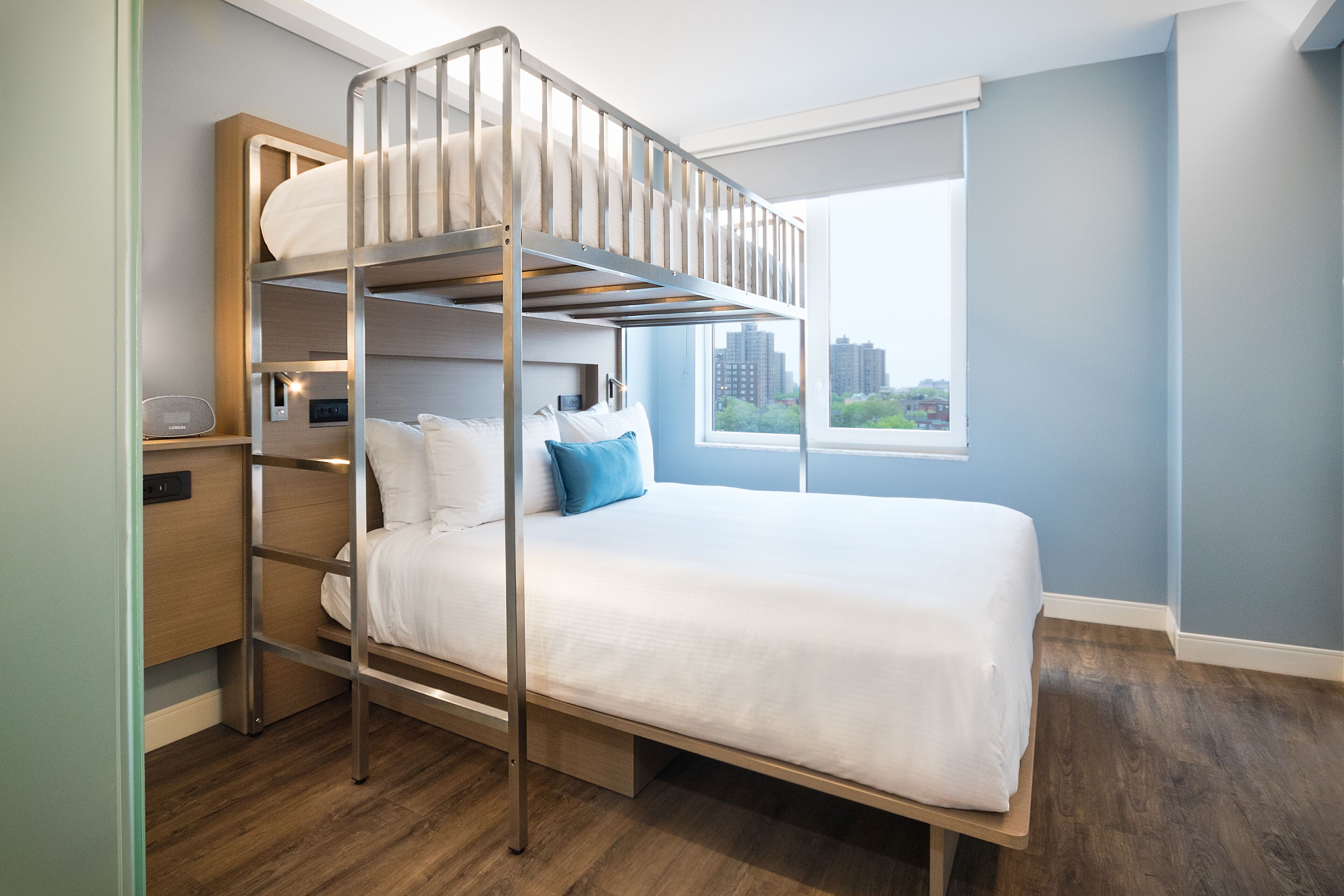 A bunk bed room with a city view, a bedside table, and a window.