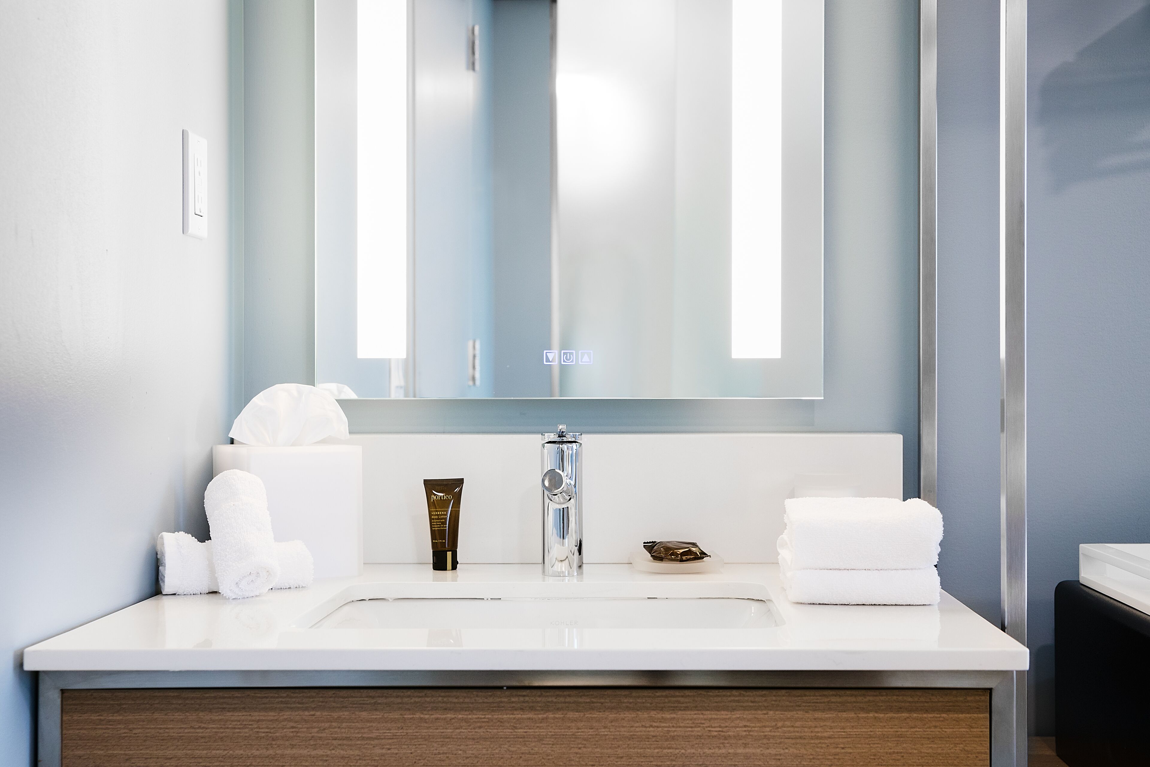 A modern bathroom with a large mirror, white sink, and neatly arranged towels.