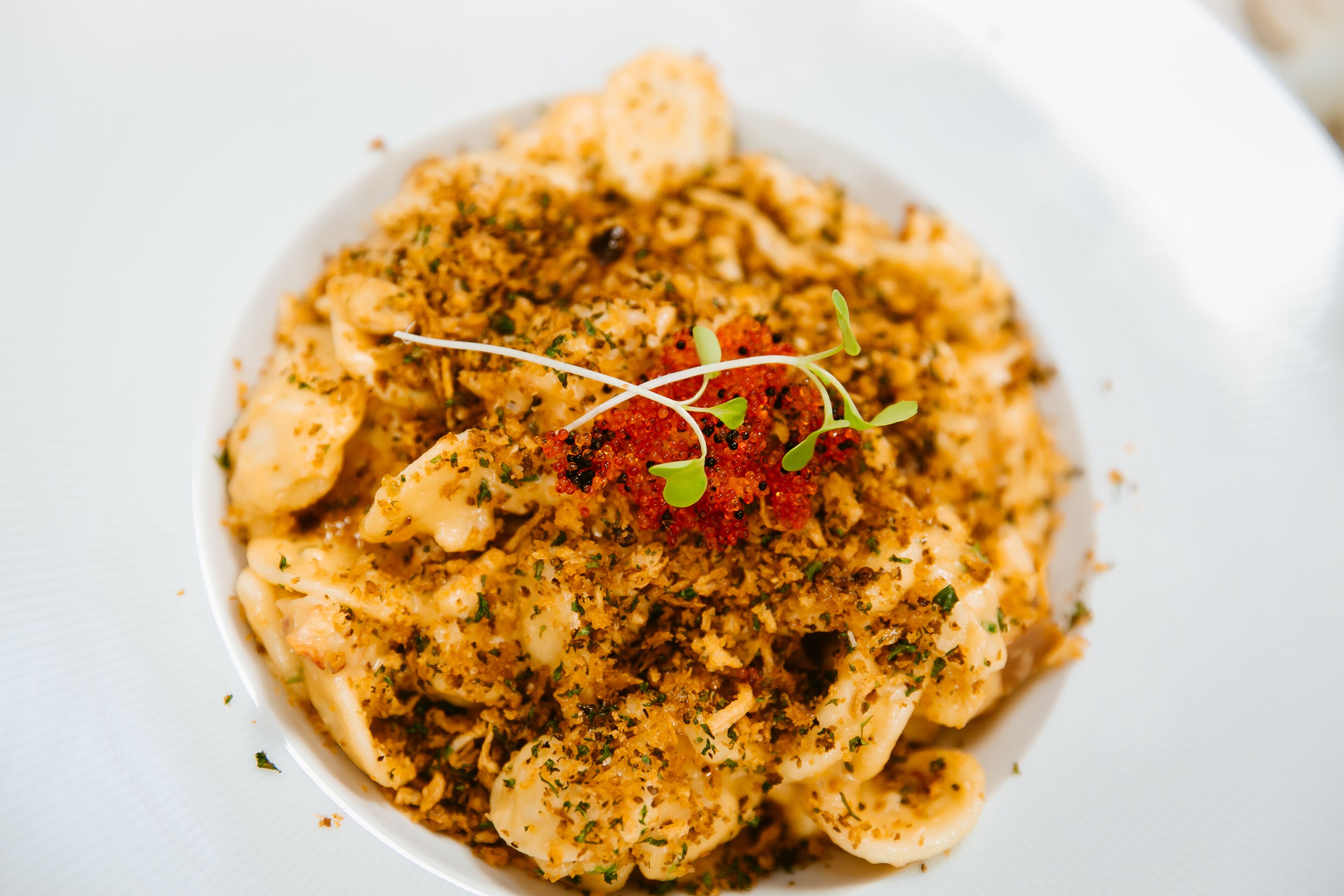 Een bord ravioli, versierd met rode kaviaar en microgroenten.