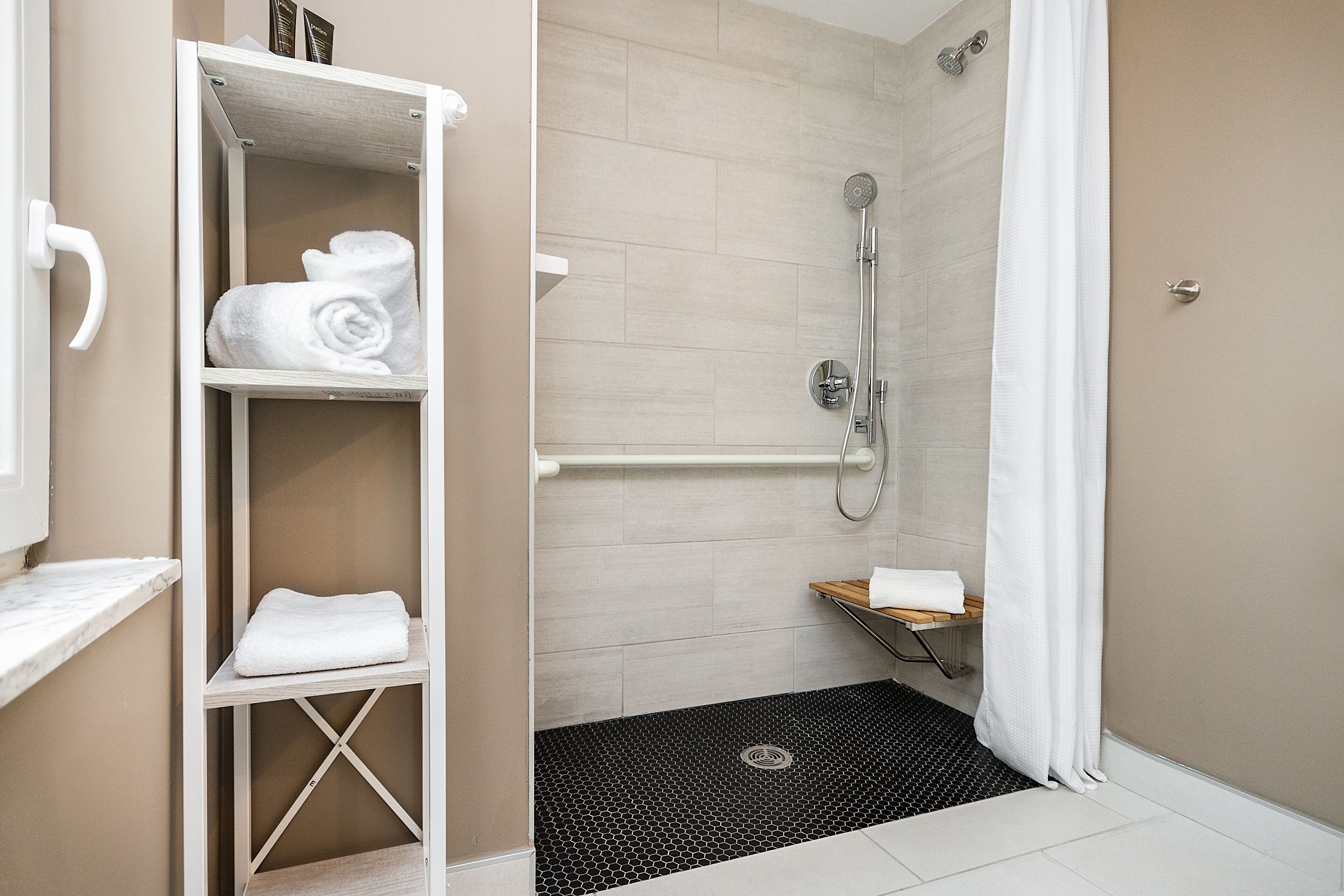 A bathroom with a shower, a towel rack, and a small shelf.