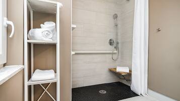 A bathroom with a shower, a towel rack, and a small shelf.