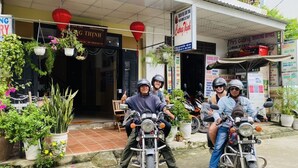 A storefront with a sign for a homestay and a booking office. - Homestay Cuong Thinh (Da Nang)