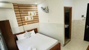 A hotel room with a large bed, a wooden headboard, a wall-mounted TV, and a bathroom visible through an open door. - Homestay Cuong Thinh (Da Nang)